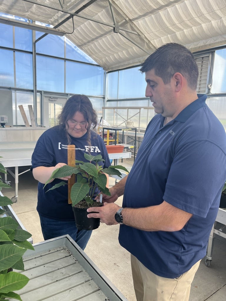 Hannah Karus (left) and her advisor, Jonathon Ganske (right), measure plants in the Beaver Dam FFA greenhouse.