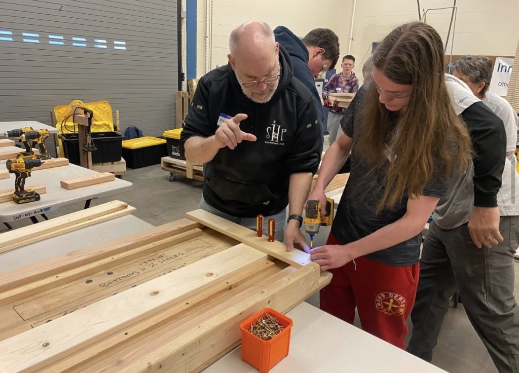 The Sleep in Heavenly Peace coordinator teaches a student how to build a bed frame.