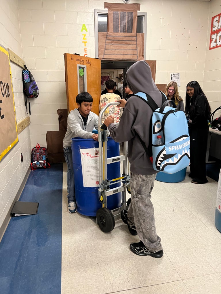 FFA member Addison Vicente helps to load a donation barrel, along with another CTSO member.