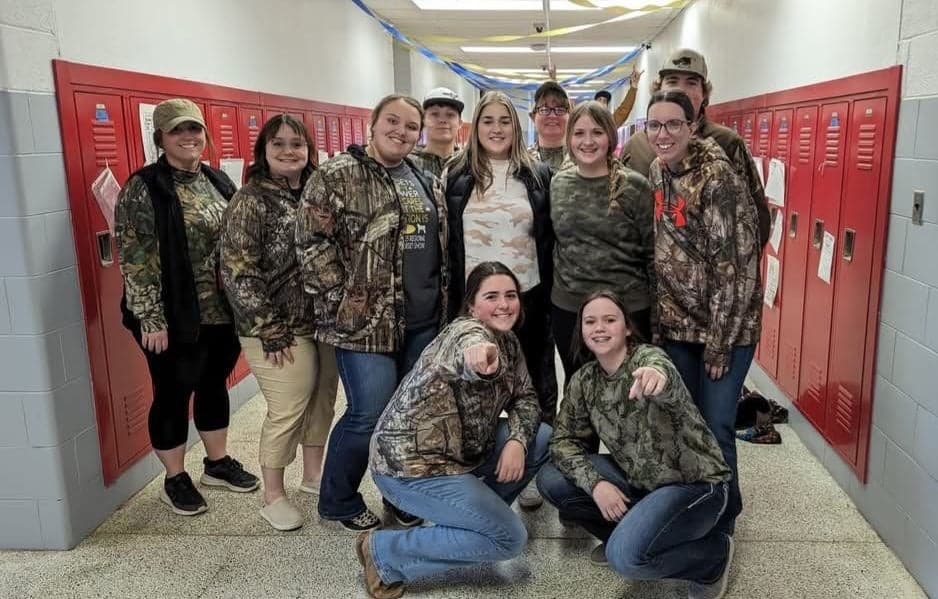 Students from the Caldwell FFA chapter stand together in a school hallway wearing camouflage clothing for Camo Day for National FFA Week.