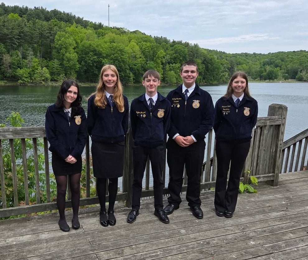 Maysville FFA officer team standing on a wooden overlook deck beside a lake while wearing official FFA jackets.