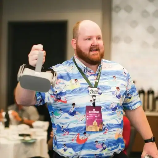 ⁠A candid photo of Dr. O.P. McCubbins smiling and speaking at an educational conference while holding up a virtual reality headset to show the audience.⁠